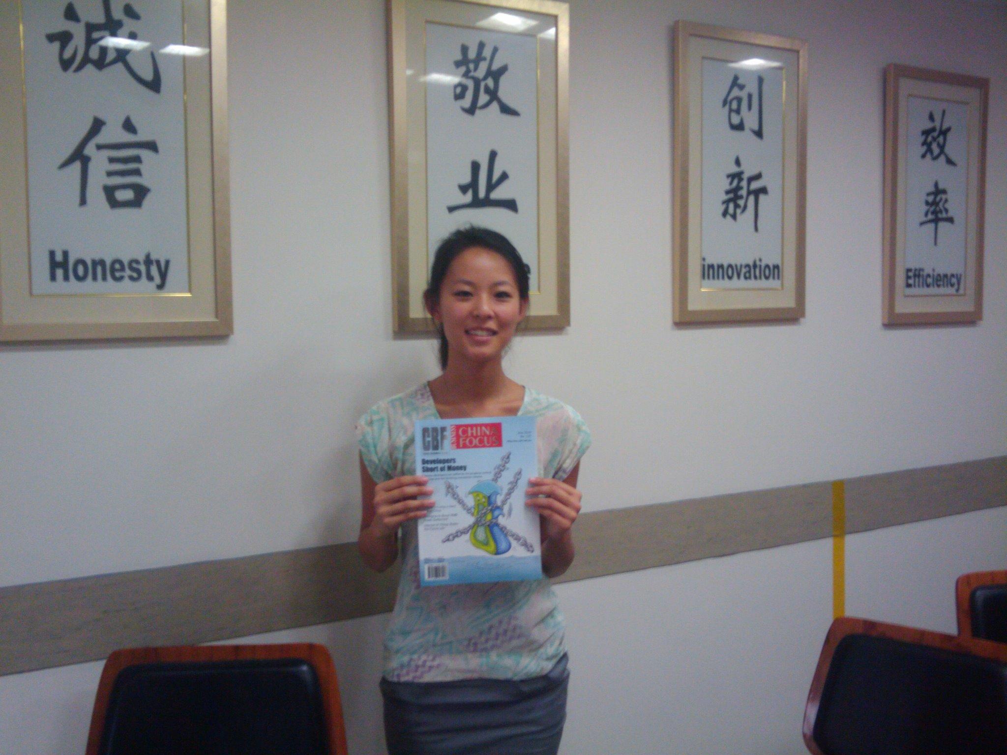 A Projects Abroad journalism intern in China poses with a magazine An intern in China takes a picture with a magazine at her placement